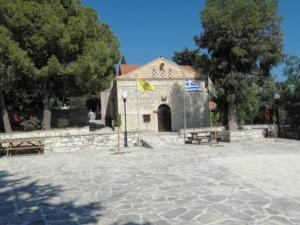 un edificio con bancos y una bandera delante de él en Stavros Agios Dimitrianos Village House en Ayios Dhimitrianos