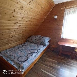 a bed in a log cabin with a window at Domki pod Honem w Cisnej in Cisna