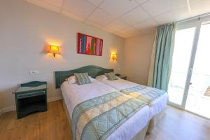 1 dormitorio con 2 camas y ventana grande en Hotel Saint Christophe, en Calvi
