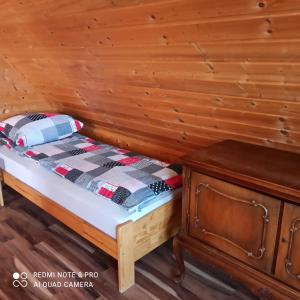 a bed in a room with a wooden wall at Domki pod Honem w Cisnej in Cisna