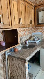 eine Küche mit einer Spüle und Holzschränken in der Unterkunft APPARTEMENT in MARTIL Complexe Résidentiel Al Karama 1 in Martil