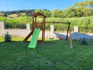 a playground with a slide in the grass at Casa Andreea in Vatra Dornei