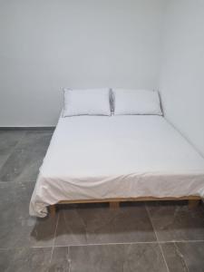 1 cama con sábanas blancas y marco de madera en מג׳יק פלייס, en Eilat
