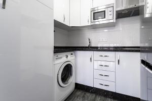 cocina blanca con lavadora y microondas en Sur Suites Palmeras 491, en Fuengirola