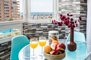 una mesa de cristal con fruta y vasos de zumo de naranja en Sur Suites Palmeras 491, en Fuengirola