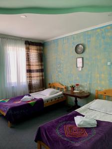 a room with two beds and a table with a table at Guest House Emily in Bokonbayevo