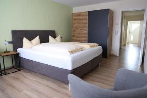 a bedroom with a large bed and a chair at Gasthaus & Pension Mohren in Pfullendorf