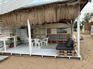 een hut met een tafel en stoelen op een strand bij Beach hub caravans Gradina in Chernomorets