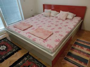 a bed with pink sheets and pillows on it at Central apartment in Gevgelija