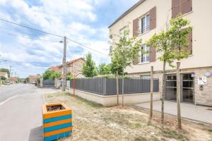 uma rua vazia com um edifício e uma cerca em Studio entre Disney, Paris et Aéroport Charles de Gaulle - Parking souterrain gratuit em Brou-sur-Chantereine