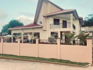 a house with a fence in front of it at Joyous AP Guest House in Aburi