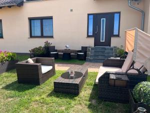 eine Terrasse mit Korbstühlen und Tischen im Gras in der Unterkunft Ferienwohnung PuraVida Ostsee 5A in Kühlungsborn