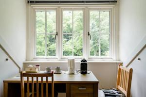 a table with two chairs and a window in a room at Roselands B&B Henley on Thames in Nuffield