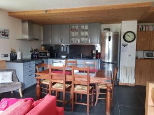 a kitchen with a table and chairs and a refrigerator at bel appartement , son jardin et le lac in Chamonix-Mont-Blanc