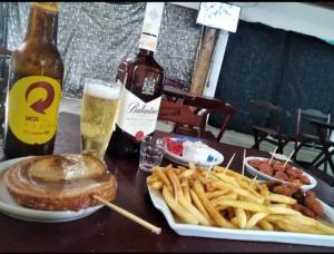 una mesa con un sándwich y papas fritas y una botella de cerveza en PousadaTopFest, en Poços de Caldas