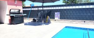 a pool with an outdoor grill and an umbrella at Apartmani Radmila in Nova Vas