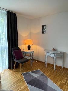 ein Wohnzimmer mit einem Tisch, einem Stuhl und einer Lampe in der Unterkunft Oasi 2 in Kreuzlingen