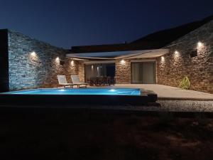 een zwembad voor een gebouw 's nachts bij Gray and Blue in Ándros