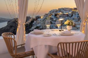 a table with wine glasses and a view of a city at Aspaki by Art Maisons in Oia