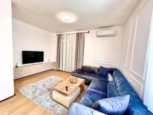 uma sala de estar com um sofá azul e uma mesa em BS Apartman em Podgorica