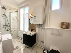 uma casa de banho branca com um lavatório e um chuveiro em The Jungle Flat em Rouen