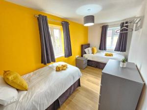 a bedroom with two beds and yellow walls at Amazing 4BR Near Hospital, Free Parking, Sleeps 10 in Laindon