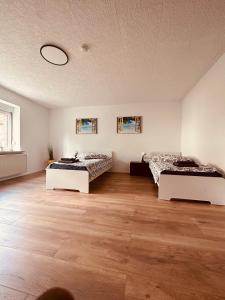 two beds in a large room with wooden floors at Villa 12 in Ketzin