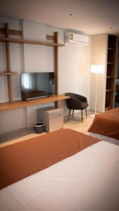 Habitación con cama, TV y silla. en Urban Suites Oliva en Oliva