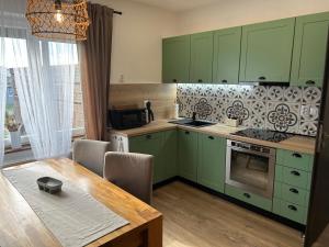 a kitchen with green cabinets and a wooden table at Apartmány Silvestr in Dolní Rychnov