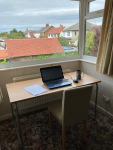 een laptop op een bureau voor een raam bij Quiet flat with parking in Cleveleys