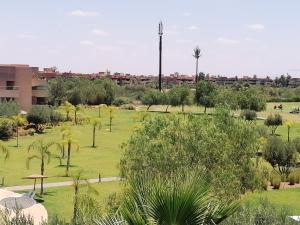 a park with palm trees and a building at Appartement prestigia jade marrakech in Marrakesh