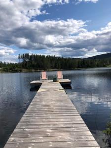 a dock with two chairs sitting on top of a lake at Unik overnatting i Stabbur/Minihus in Lunde