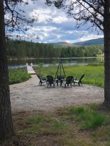 un grupo de bancos en un parque cerca de un lago en Unik overnatting i Stabbur/Minihus, en Lunde