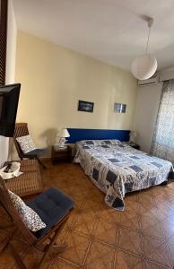 a bedroom with a bed and a chair and a tv at Al Porto Di Roma B&B in Lido di Ostia