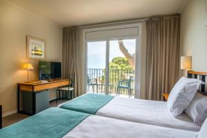 a hotel room with a bed and a desk and a window at Hotel Hostalillo by Escampa Hotels in Tamariu