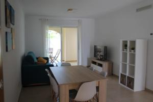 sala de estar con mesa de madera y sillas en Apartamento nuevo en urbanización a 250 metros de la playa, en Denia