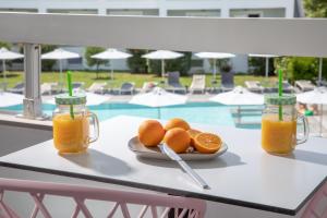 une plaque d'oranges sur une table à côté d'une piscine dans l'établissement La Maison Corfu - Adults Only, à Ýpsos