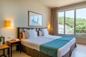 a hotel room with a bed and a large window at Hotel Hostalillo by Escampa Hotels in Tamariu