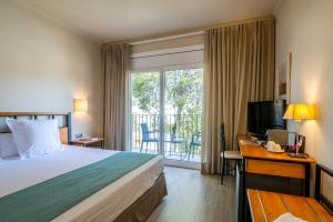 a hotel room with a bed and a desk and a balcony at Hotel Hostalillo by Escampa Hotels in Tamariu
