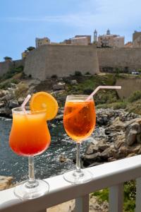 dos vasos de zumo de naranja y una rodaja de naranja en una barandilla en Hotel Saint Christophe, en Calvi