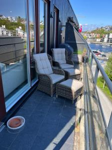 un balcón con 2 sillas y un sofá en un edificio en Koselig leilighet på Bystranden en Kristiansand