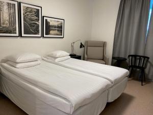 a bedroom with a large white bed and a chair at Hotell Mörby - Danderyd Hospital in Danderyd