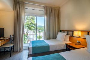 a hotel room with two beds and a window at Hotel Hostalillo by Escampa Hotels in Tamariu