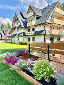a park bench in front of a building with flowers at Nosal Ski & Wine Apartments in Zakopane