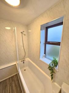 a bathroom with a tub and a shower and a window at Amazing 6BR, Sleeps 10, Large Garden, Free Parking 