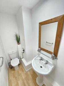 a bathroom with a toilet and a sink and a mirror at Amazing 6BR, Sleeps 10, Large Garden, Free Parking 