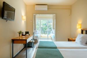 a hotel room with a bed and a desk and a window at Hotel Hostalillo by Escampa Hotels in Tamariu