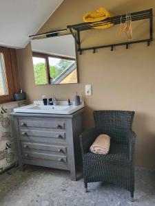 a bathroom with a sink and a chair and a mirror at A la salle de jeux in Dinant