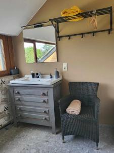 a bathroom with a sink and a chair and a mirror at A la salle de jeux et son jardin autour de la cabane verte in Dinant