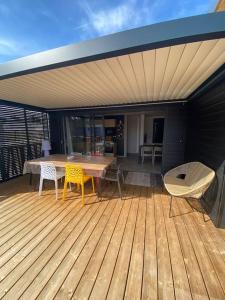 una terrazza in legno con tavolo e sedie. di Cottage "SANS SOUCI" chaleureux à 150m de la plage a Jullouville-les-Pins